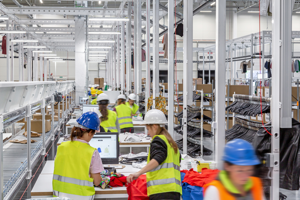 Pakkauspöytiä pitkässä rivissä verkkokaupan palautuskeskuksessa tuotteiden käsittelyä varten.