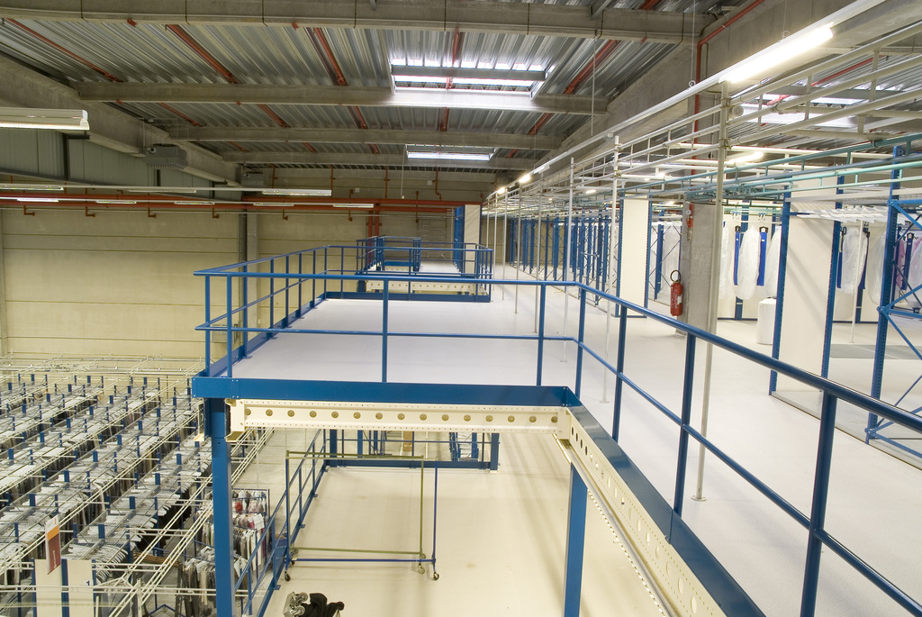 Kolmikerroksinen välitaso pientavarahyllyillä ja sinisillä kaiteilla varaston tilankäytön tehostamiseen.