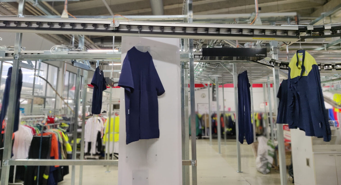 Garment conveyor taking dry cleaned hanging garments trough RFID station in an industrial laundry